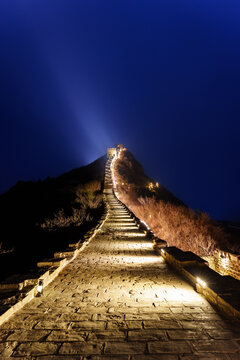A Majestic Nightscape View of the Great Wall of China Illuminated with Warm Lights, Leading the Eye Up a Mountain Ridge Against a Deep Blue Twilight Sky