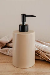 Ceramic soap dispenser with black pump on a wooden countertop © Diana Vyshniakova