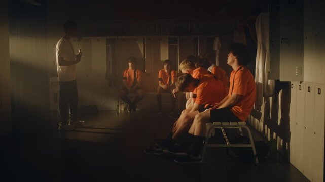 After Match Loss, Coach Addresses Dejected Team Athletes in Locker Room. Players Scattered and Despondent. Man Feedback, Delivered With Supportive Gestures, Aims to Build Character, Set New Goals.
