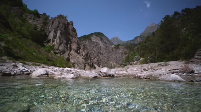 Clear alpine mountain river water rushing towards camera over pebbles. Dolomites, Italy. Low angle view