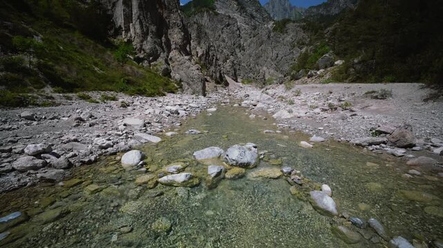 Crystal clear mountain stream water flowing over pebbles near Aviano, Friulian Dolomites, Italy.