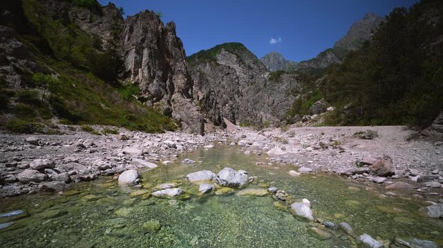 Clear alpine mountain river water flowing towards camera over riverbed gravel, Friulian Dolomites, Italy.