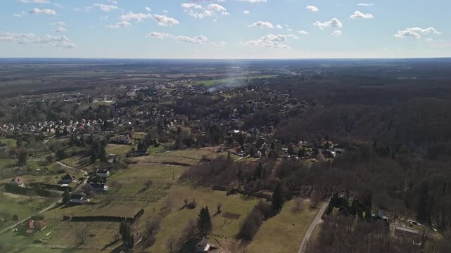 Zalakaros thermal spa town in Zala County, Hungary, with residential areas, forests, fields and rolling hills under a clear winter sky, viewed by drone.