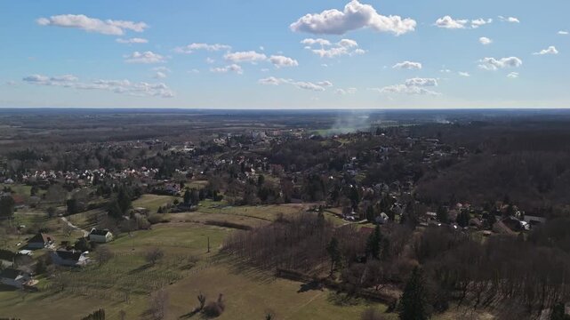 Zalakaros thermal spa and residential areas in Zala County, Hungary, surrounded by forests, fields and hills under a clear winter sky, captured in a wide drone panorama.