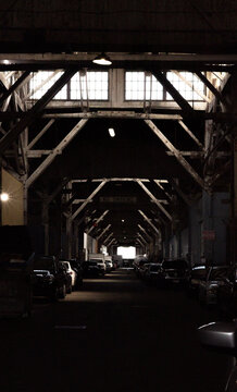 Dark Warehouse Interior with Wooden Trusses and Parked Cars