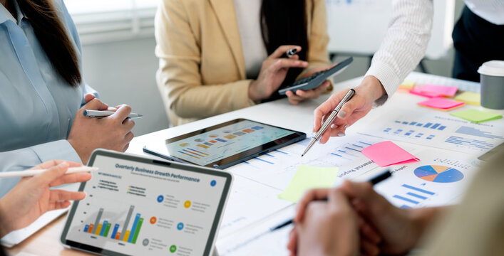 Business team brainstorming and analyzing quarterly financial growth charts on desk.