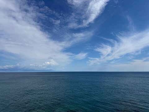 Open sea blue calm waters and blue sky with fluffy beautiful clouds.