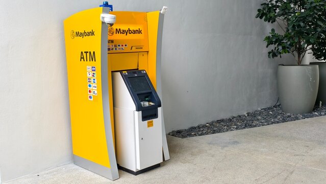 Ipoh,Malaysia - 22 July 2026: A stand-alone yellow Maybank ATM machine positioned outdoors near a potted plant.