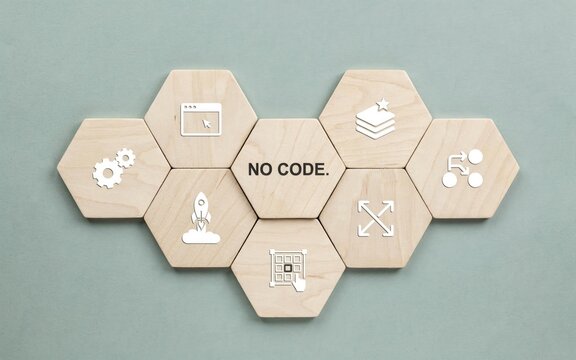 Wooden hexagonal tiles featuring no code concept icons arranged on a soft light green background