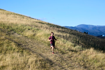Obraz premium Young man running up grassy hill trail