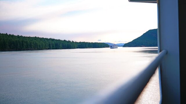 Distant passenger ferry navigating scenic coastal island channel at sunset