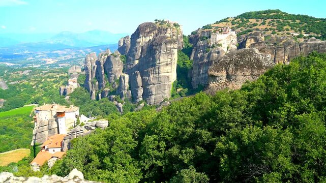 Meteora, Kalabaka, Greece. Sandstone pillars crowned with Greek Orthodox monasteries, panoramic view across the Thessalian valley under clear summer sky