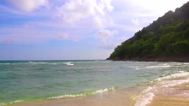 Sun turquoise blue clear water waves rocks Merlin Beach Thailand.