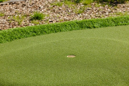 Golf course green with putting hole and rough ground