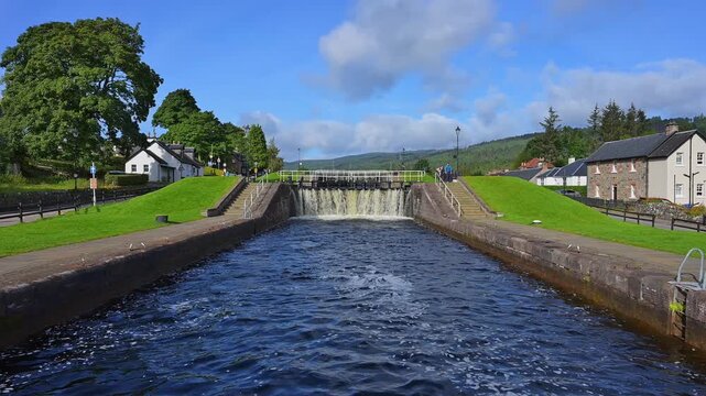 Eine Schleuse mit rauschendem Wasser, umgeben von B&auml;umen und einer H&uuml;gellandschaft, Kaledonischer Kanal, Fort Augustus, Loch Ness, Schottland, Vereinigtes K&ouml;nigreich, Gro&szlig;britannien