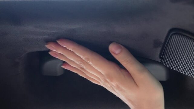 Female hand gently glides across the soft Alcantara headliner of a luxury car. Close-up highlighting premium suede-like material, refined craftsmanship, elegant interior design and tactile automotive 