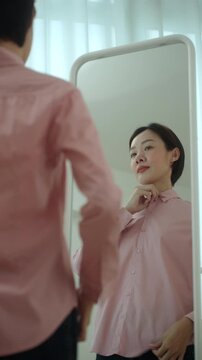Woman getting dressed in front of a mirror in a modern dressing room. Morning routine capsule wardrobe, personal styling, fashion confidence. Self-care and everyday lifestyle concept.

