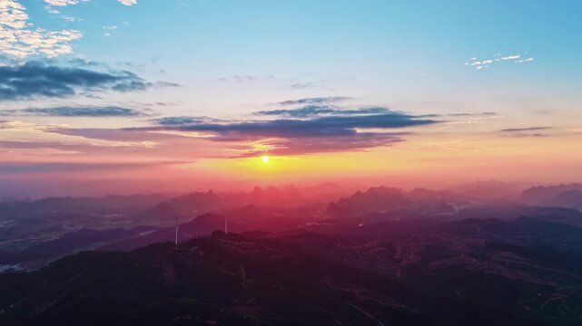 Dramatic Sunset Time-Lapse: Sun Emerging from Clouds Over Karst Mountains with Wind Turbines, Golden Light Expanding and Receding
