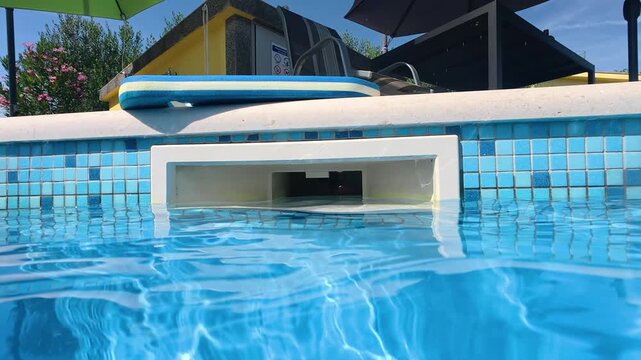 Close-up of a swimming pool water filter outlet integrated into the pool wall. Summer concept of pool maintenance, water circulation, filtration, and clean swimming water.