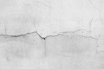 Fototapeta premium Cracked white wall surface detail with rough texture and linear fissures.