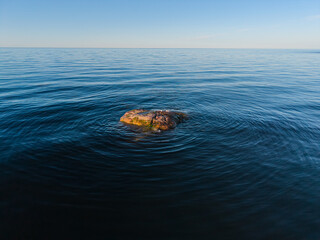 Single granite boulder in calm blue sea water coastal nature exploration © Maddi