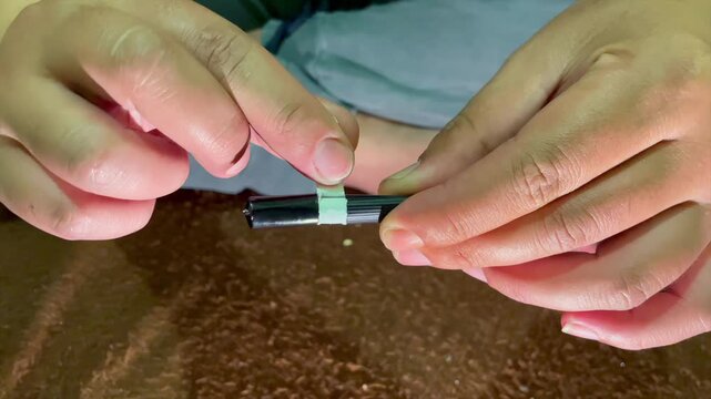 Hands opening plastic wrapper of a single cigarette