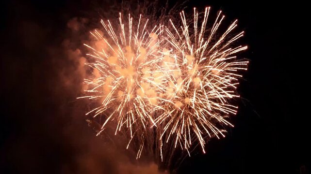 A spectacular fireworks display transitions from brilliant purple bursts to cyan trails and shimmering gold explosions in the night sky