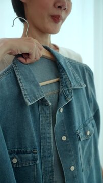 Close-up Woman choosing and trying on clothes in front of a mirror at home. Outfit selection. Capsule wardrobe, personal styling, sustainable fashion. Self-confidence and morning routine concept.
