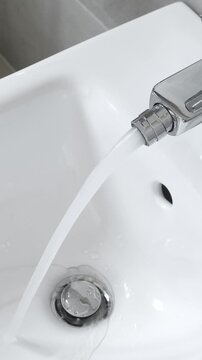 White ceramic bidet at restroom interior. Water is running. Nobody. Vertical footage