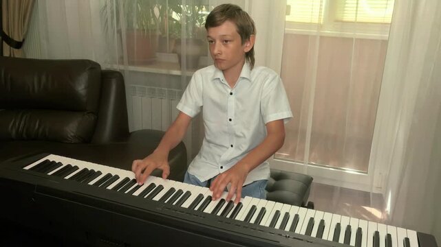 Focused Teenage Boy Playing Digital Piano At Home
