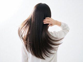 Fototapeta premium 指先で髪に触れながら風になびく美しいストレートヘアの後ろ姿の女性
