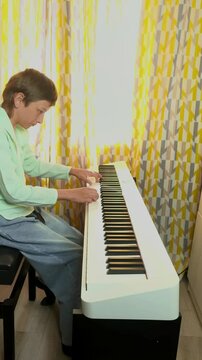 Teenage Boy Practicing Digital Piano At Home
