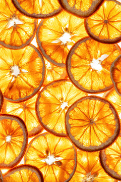 Close-up round orange fruit slices as minimal food pattern, backlit lighting. Healthy citrus fruit details photo for vegan, organic, clean eating, and fresh juice concepts. Bright yellow orange color.