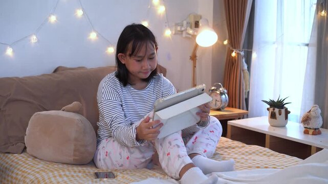 Modern Lifestyle and Relaxation, Young girl lies comfortably on bed using a tablet in a cozy bedroom