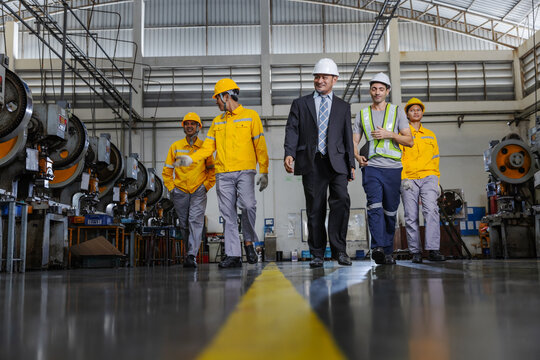 Manufacturing Team Walking Together on Industrial Factory Floor with Engineering Leadership