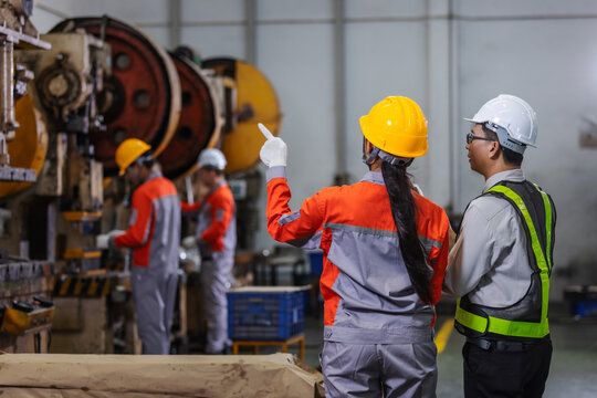 Manufacturing engineers supervising production activities on an industrial shop floor while monitoring machine operations and workforce performance.