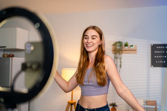 Caucasian woman content creator recording video on mobile phone in house.