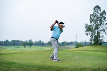 Obraz premium Professional young male golfer swings his club on scenic golf course. 