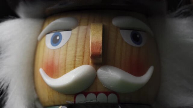 A close-up shot of the face of a wooden nutcracker doll featuring intricate details on its painted face and hair.