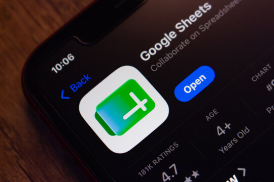 Mexico City, MEXICO - Jul 7 2026 : Close-up of a smartphone displaying the Google Sheets app listing on the Apple App Store, on a wooden surface.