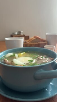 A steaming bowl of traditional Russian soup with meat and vegetables sits on a wooden table in Khuzhir, Irkutsk Oblast, Russia