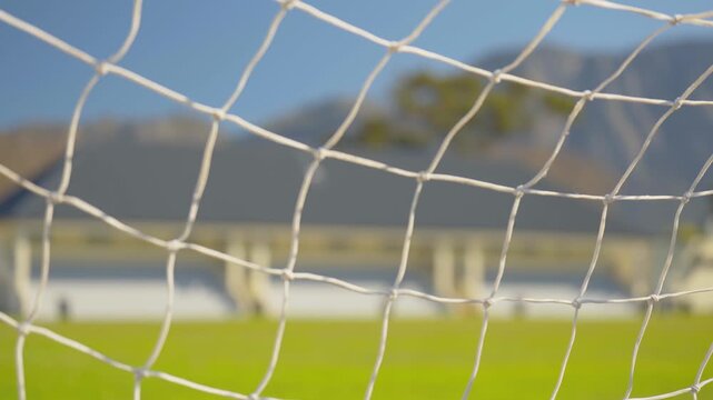 An abstract focus rack shot through a football net of a field.