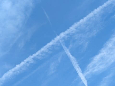 Blue Skies with wispy chemtrail aeroplane lines and fluffy white clouds