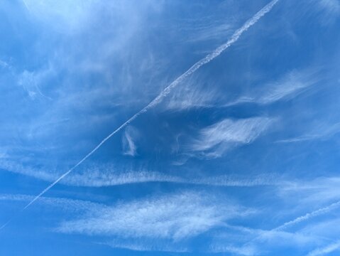 Blue Skies with wispy chemtrail aeroplane lines and fluffy white clouds