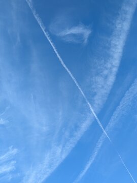 Blue Skies with wispy chemtrail aeroplane lines and fluffy white clouds