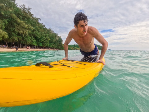 Caucasian young man lying on a paddleboard gliding over the ocean waves.