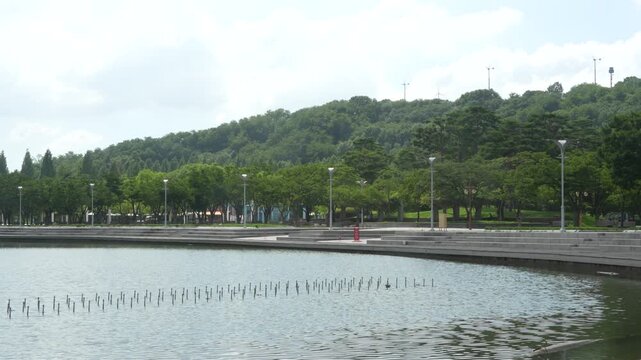분수가 있는 공원 호수와 숲이 우거진 언덕 풍경