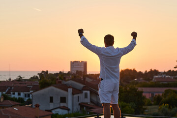 Obraz premium Man Celebrating On Rooftop Terrace Overlooking Sea View At Sunset — Success And Freedom
