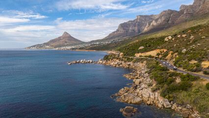 Scenic winding coastal road south of Camps Bay, South Africa, beneath a clear blue sky. Lion's Head and Camps Bay form a spectacular backdrop to one of Cape Town's most iconic coastal drives.