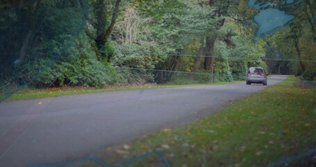 Obraz premium Entering left, silver van moving right along tree-lined road, faint map overlay guiding route